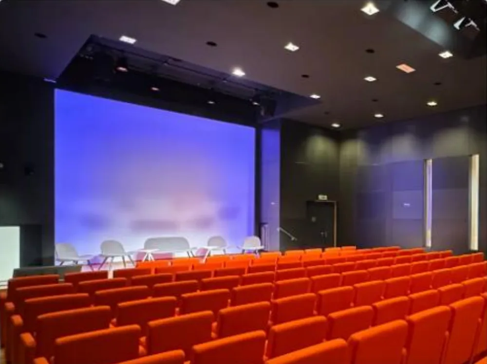 Salle de conférence aux fauteuils rouges face à la scène
